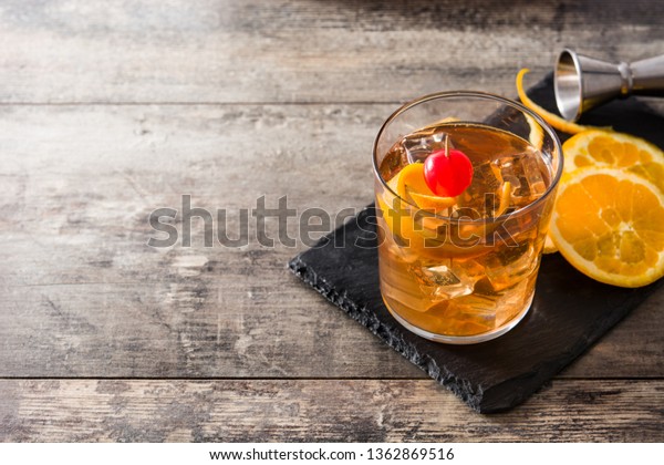 Old fashioned cocktail with orange and cherry\
on wooden table. Copyspace