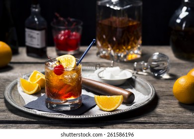 Old Fashioned Cocktail In Vintage Inspired Bar With Liquor Bottles And Ingredients