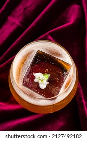 Old Fashioned Cocktail With Whiskey, Classic Old Fashion With A Piece Of Ice On Red Velvet, Retro Crystal Glass Tumbler