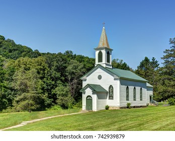 Old fashioned country church set on rolling hills with forest background 