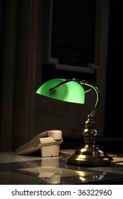 Old Fashioned Desk Lamp And Telephone On A Study Table In A Dark Room