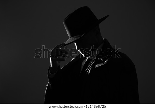 Old fashioned detective in hat on dark background,\
black and white effect