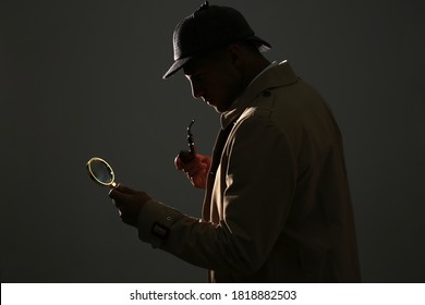 Old fashioned detective with smoking pipe and magnifying glass on dark background - Shutterstock ID 1818882503