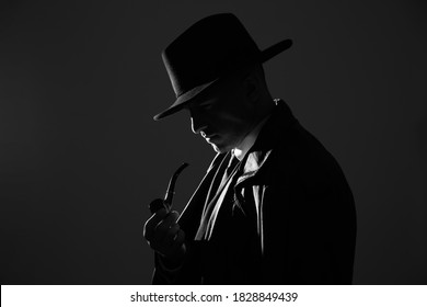 Old fashioned detective with smoking pipe on dark background, black and white effect - Shutterstock ID 1828849439