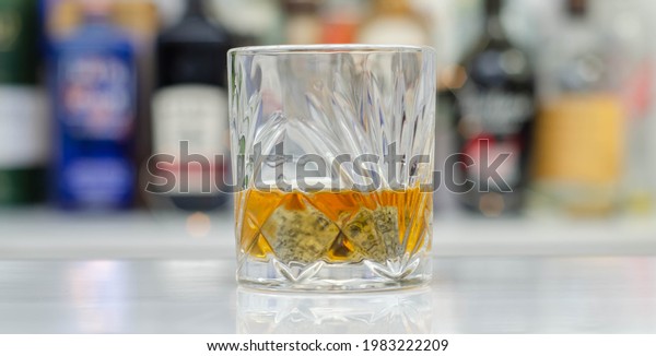 Old fashioned glass with scotch whisky\
and ice cubes on the bar, exclusive\
drink