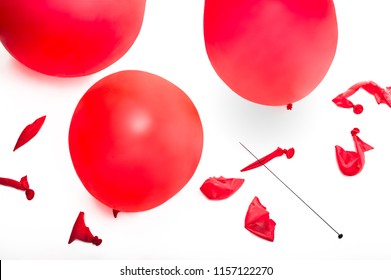 Old fashioned hat pin and a collection of popped and inflated red balloons.