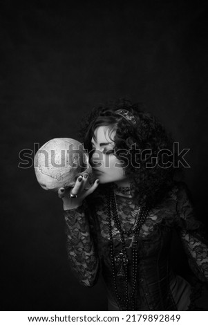 Old fashioned lady posing with skull over dark background