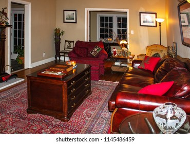 Old Fashioned Living Room At Christmas With Leather Sofa And Persian Rug And A Illuminated Christmas Village In The Background