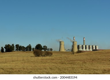 An Old Fashioned Power Station Burning Coal And Using Cooling Towers In Order To Produce Electricity In Contrast With The Grassland And Trees Around It