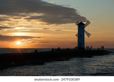 old fashioned windmill on the rocky pier at the coastline of usedom island along the baltic sea of Poland with beautiful romantic sunset and dramatic orange glowing sky in the background. - Powered by Shutterstock