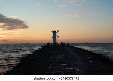 old fashioned windmill on the rocky pier at the coastline of usedom island along the baltic sea of Poland with beautiful romantic sunset and dramatic orange glowing sky in the background. - Powered by Shutterstock