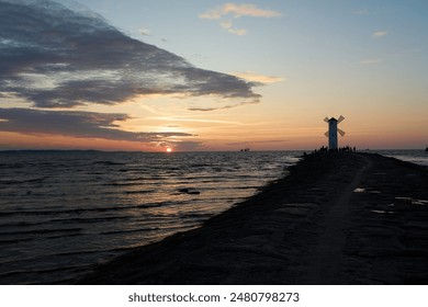 old fashioned windmill on the rocky pier at the coastline of usedom island along the baltic sea of Poland with beautiful romantic sunset and dramatic orange glowing sky in the background. - Powered by Shutterstock