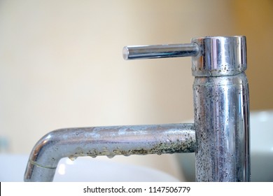 Old faucet (water tap) over sink in the bathroom. Dirt Bacteria. Hard water stain of soap and mold. Time to clean. Copy space.