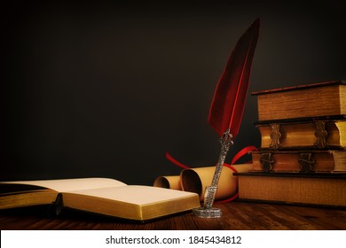 Old feather quill ink pen with inkwell and old books over wooden desk in front of black wall background. Conceptual photo on history, fantasy, education and literature topic.