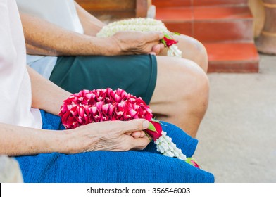 Old Female Hand Holding Rose Garland And Blurred Old Male Hand Holding Jasmine Garland. Thai Tradition For Any Special Family Occasions When Younger Pay High Respective To There Older Family Members.