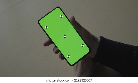 old female hands holding smartphone with green screen over wood vintage table with dim window light, wide photo - Shutterstock ID 2192325307