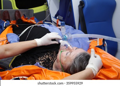 Old female lying on stretcher in the ambulance with oxygen mask on face - Powered by Shutterstock