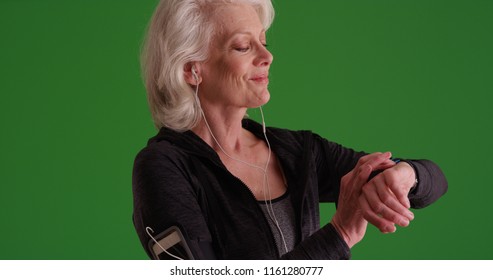 Old Female Runner Checking Watch Before Exercising On Green Screen