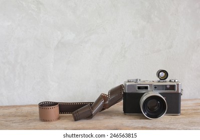 Old Film Camera And A Roll Of Film On Wood