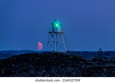 Old Finnish Lighthouse On Cape Kurkiniemi And The Rising Red Moon, Lake Ladoga, Republic Of Karelia, Russia