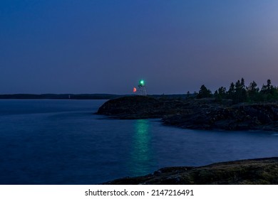 Old Finnish Lighthouse On Cape Kurkiniemi And The Rising Red Moon, Lake Ladoga, Republic Of Karelia, Russia