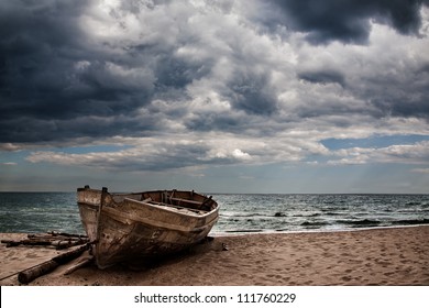 An Old Fishing Boat On The Beach. Stormy Skies.