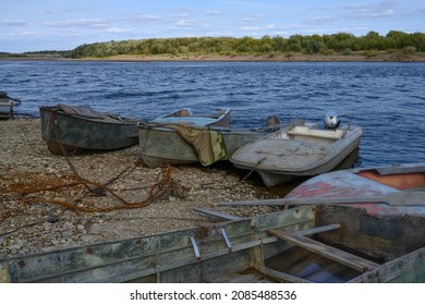 Old fishing boats on the banks of the Kolva River (Perm Territory, Russia) in a summer morning. Landscape with boats, pebble shore and forest in the distance. The inside of the boat is visible 