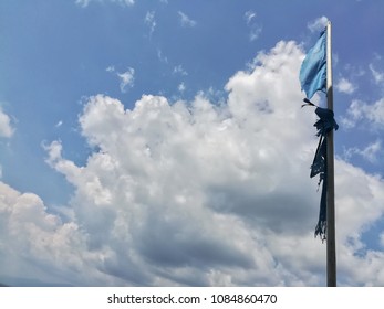 Old flag on the blue cloudy sky.