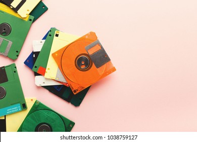 Old floppy disks isolated on pink background. Border of magnetic retro storage devices, cutout of colorful diskettes, copy space, flat lay, top view