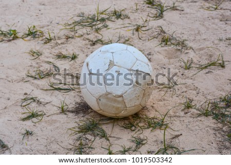 Old football leaked left in the sand field.
