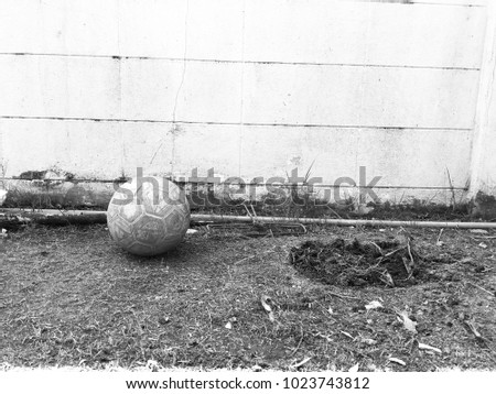 Old football is placed next to the wall with black and white tone.