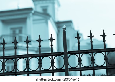 Old Forging Gate With Ornament Of Entry To Abandoned Manor, Castle Or Victorian House.  Aged Photo. Cold Blue Filter. Blurred Tree In Background.