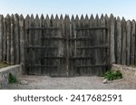 Old fortification stockade made of sharpened logs and wooden gates with forged hinges