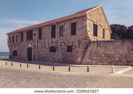 Old fortress with shutters on windows and wooden entrance door of medieval royal fort in Byzantine style made of stone paving stones on shores of Mediterranean Sea under blue sky (Larnaca, Cyprus)
