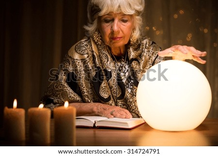 Old fortune teller is learning how to use crystal ball