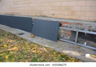 Old Foundation Renovation By Installing Vertical Steel Siding, Metal Siding On A Starter Strip To Protect The House From Water Damage. 