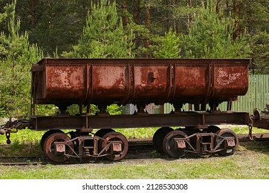 Old freight wagon - platform for narrow-gauge railways on the background of nature. Retro technology rusted and abandoned