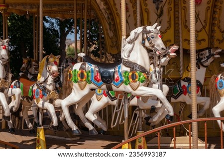 Old French carousel in a holiday park during sunny day. Horses on a traditional fairground vintage carousel. Merry-go-round with horses. Vintage carousel horse