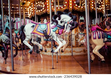 Old French carousel in a holiday park. Three horses and airplane on a traditional fairground vintage carousel. Merry-go-round with horses. 