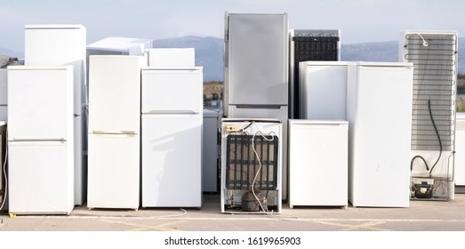 Old fridge freezer refrigerator refrigerant gas at refuse dump skip recycle stacked pile plant help environment reduce pollution white silver 