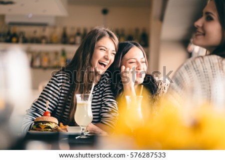 Old friends meeting up after long time for drinks and eating, talking about their memories. Girlfriends showing signs of affection, reliving beautiful moments from the past, being happy.