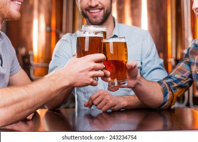 Old Friends Meeting. Close-up Of Three Happy Young Men In Casual Wear Toasting With Beer While Sitting In Beer Pub Together