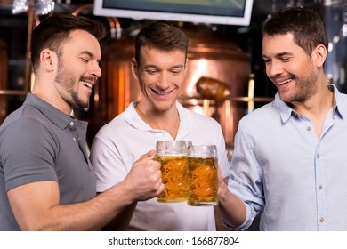 Old Friends Meeting. Three Cheerful Young Men Drinking Beer In Bar