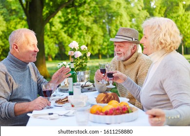 Old friends are sitting while drinking coffee with red wine in the garden in summer - Powered by Shutterstock