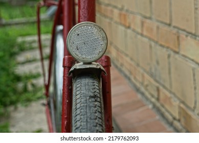 old front iron bicycle white reflector on an old red color iron bicycle stands near a brick wall on the street in summer