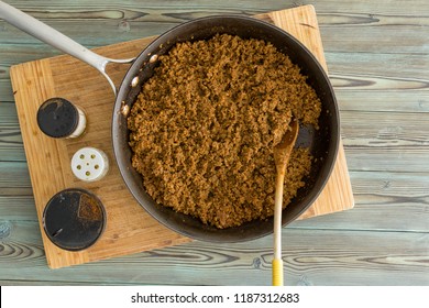 Old Frying Pan Filled With Savory Seasoned Cooked Ground Beef For Sloppy Joe Tacos Alongside Assorted Condiments In An Overhead View On A Wooden Board On A Kitchen Table