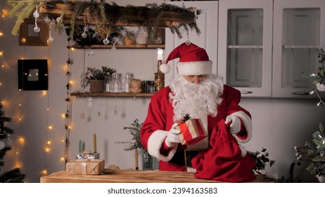 Old funny Santa Claus, puts gift boxes in a bag. Family favorite winter holiday. Christmas gifts from Santa. Merry Christmas. Santaclaus gift delivery. Festive New Year mood. Santa Claus brings gifts