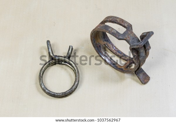 Old garden accessories. Rusty hose clamps on\
the workshop table. Light\
background.