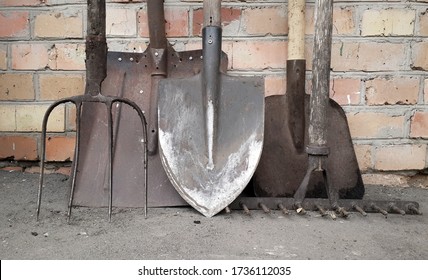 Old Garden Tools . Dirty Rusty Shovels,  Rake And Pitchfork On Brick Wall Background