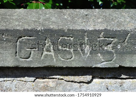 Old Gas Utility Sign Carved into Stone Coping  on Wall 